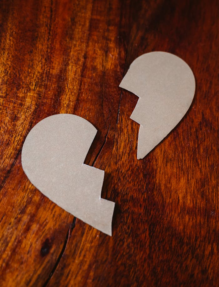 heros-img Cardboard broken heart symbol on wooden table, representing love and separation.